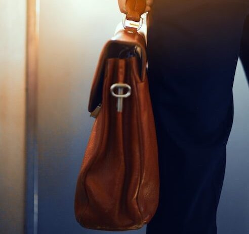 brown leather case hands man cropped picture businessman suit standing subway train holding brown bag his hand_549566 885 e1781817431971